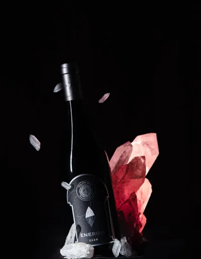 Mise en scène d'une bouteille de vin avec des cristaux de quartz en lévitation, réalisée par un photographe à Annecy