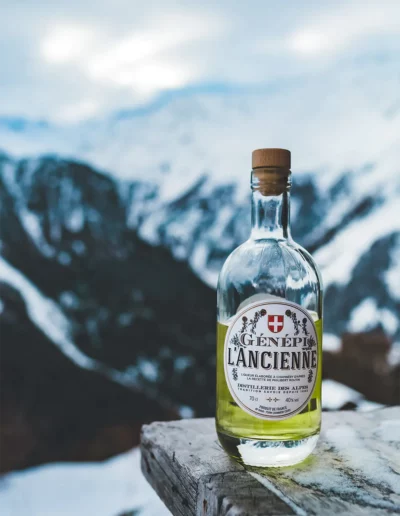 Mise en scène d'une bouteille de Génépie devant la montagne, réalisée par un photographe à Annecy