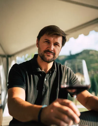 reportage photographique d'un vigneron qui regarde l'objectif avec un verre de vin rouge à la main, réalisé par un photographe à Annecy