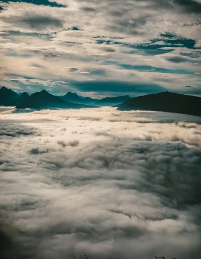 une mer de nuage opaque bercé par une lumière chaude et des montagnes en arrière-plan
